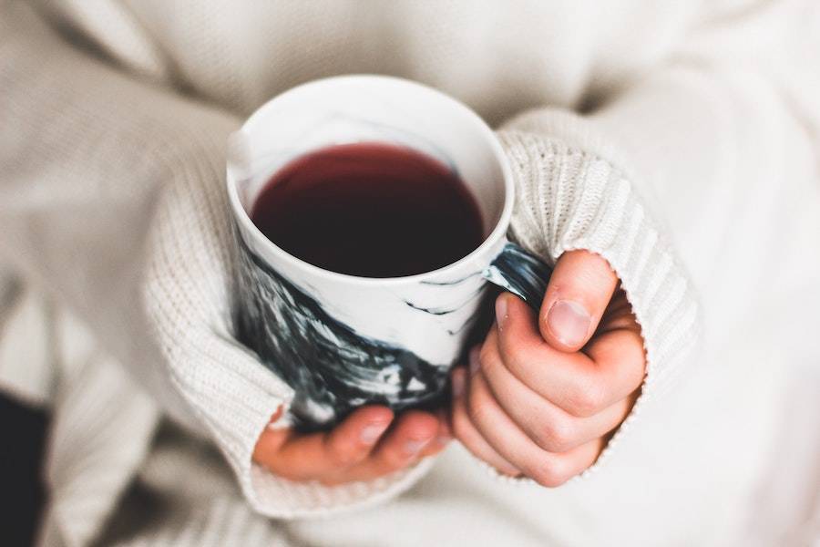 Hands holding coffee cup to help with Raynaud's in the office | Photo by Kira Auf Der Heide for Unsplash